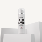 REBELX Clear SPF50 sunscreen with 24% zinc in white pump tube displayed on white geometric platforms, 2 oz size