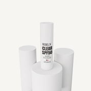 REBELX Clear SPF50 sunscreen with 24% zinc in white pump tube displayed on white geometric platforms, 0.5oz size