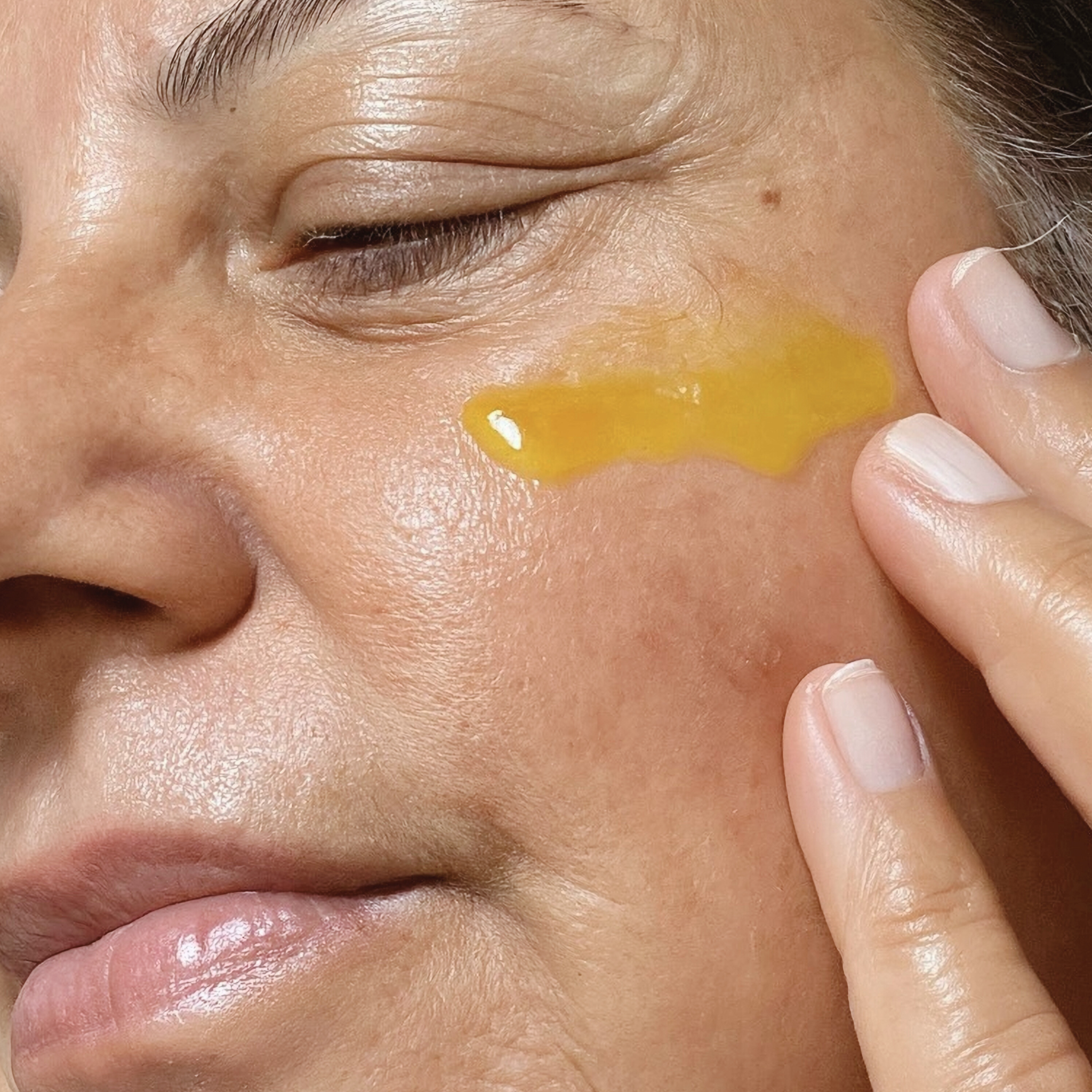 Close-up of a woman applying a retinol to their face