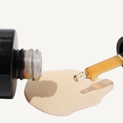 REBELX Retinol serum texture shot showing golden amber oil with glass dropper dispensing product onto white surface