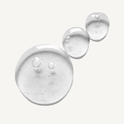 Clear serum texture with water droplets on white surface showing lightweight, hydrating formula consistency